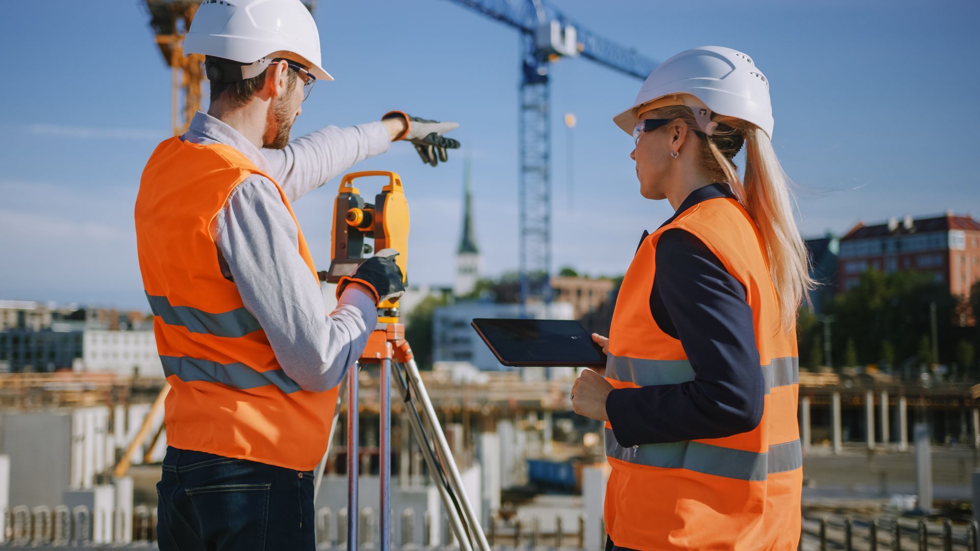 Surveyors using theodolite surveying optical instrument on a construction site.