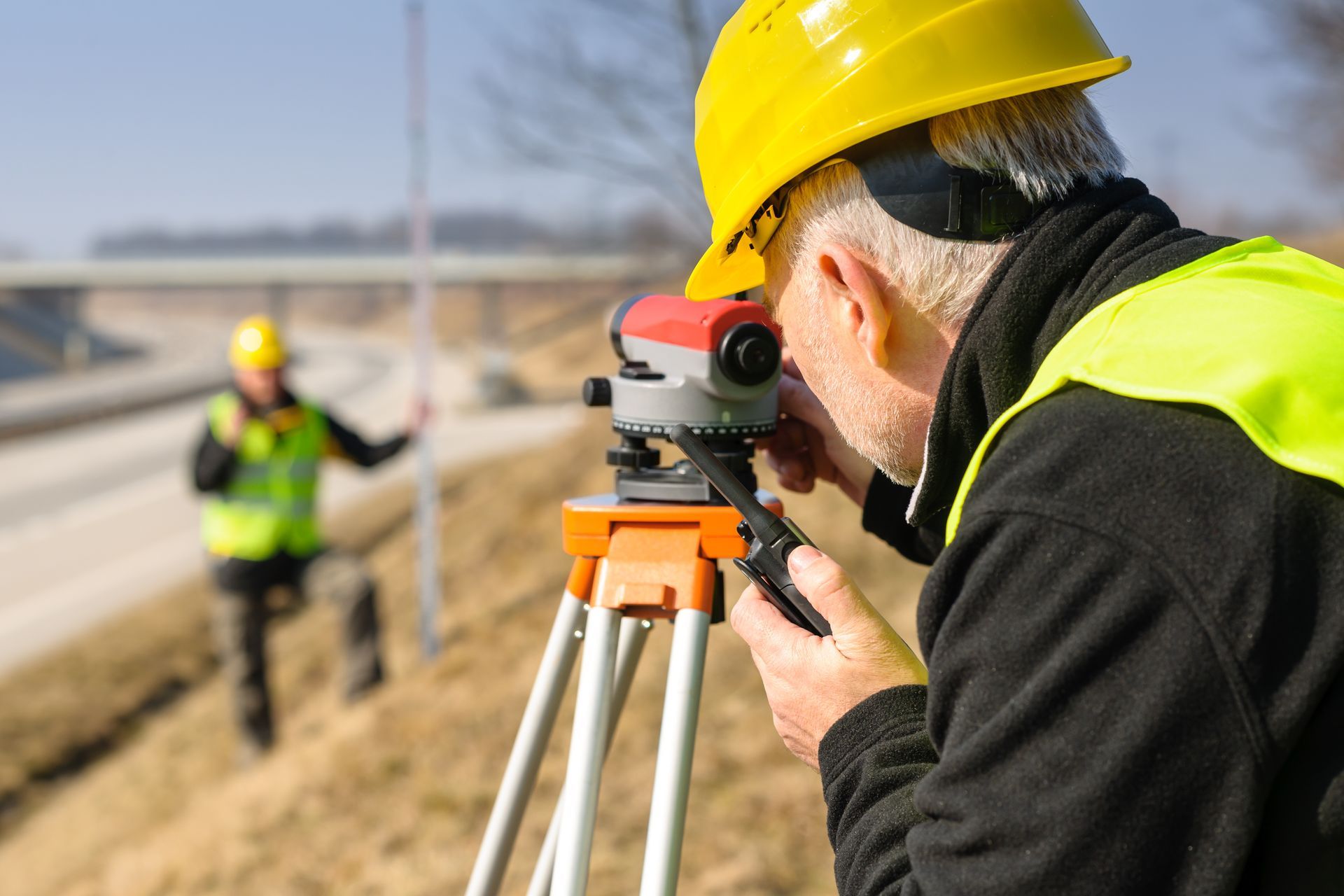 A man is using an optical level to ensure accuracy in their measurements.