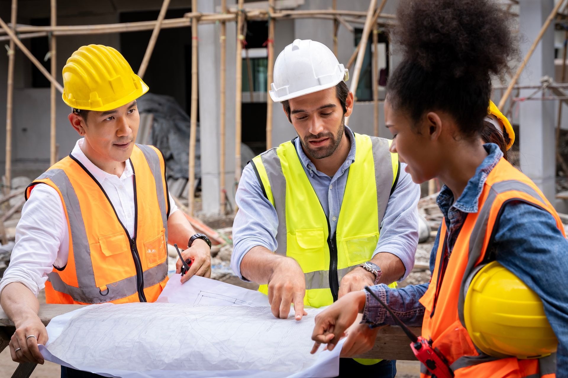 A team of civil engineers is checking and discussing a blueprint at a construction site. A team of civil engineers is checking and discussing a blueprint at a construction site.