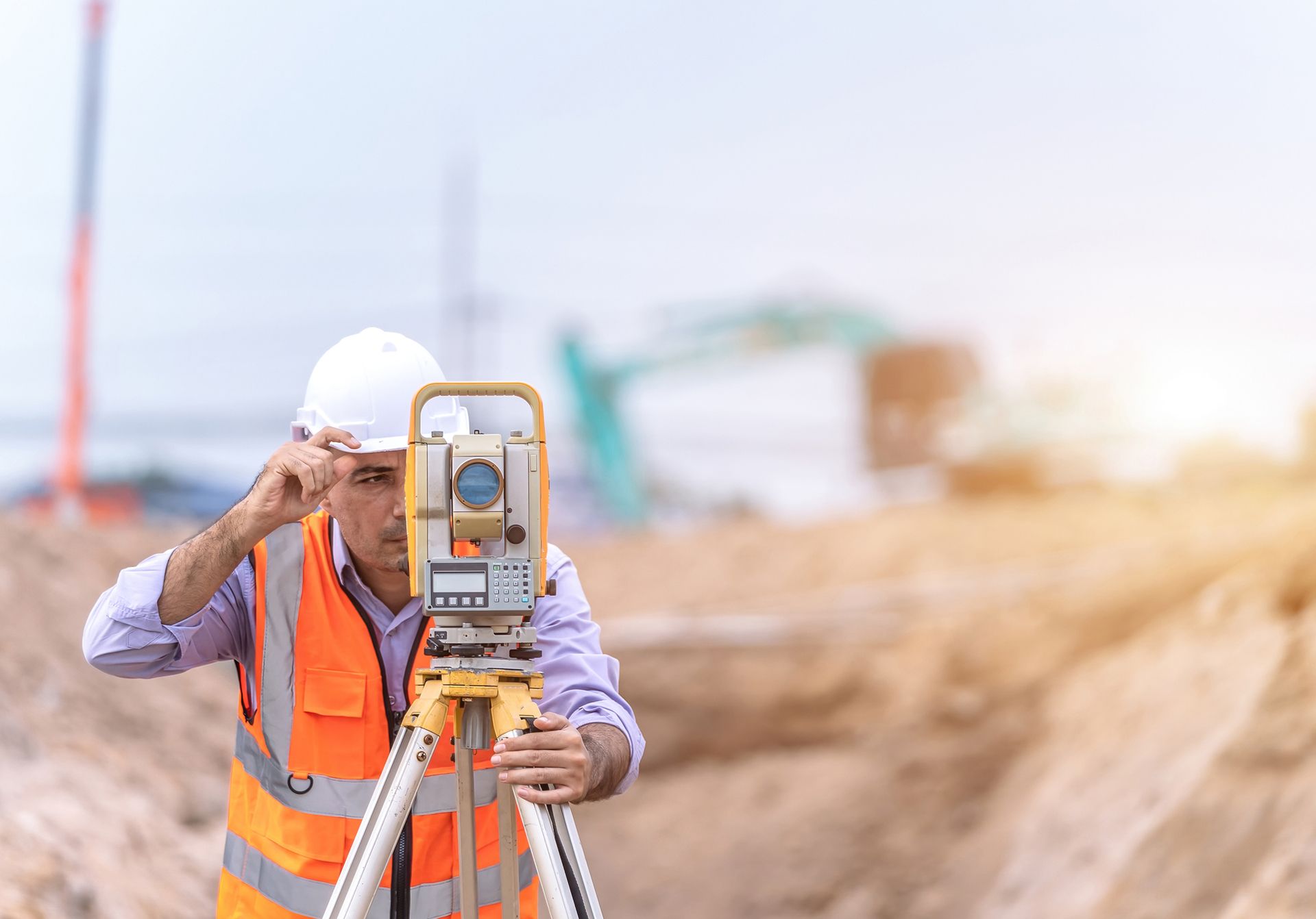 Surveyor and survey equipment on construction site.