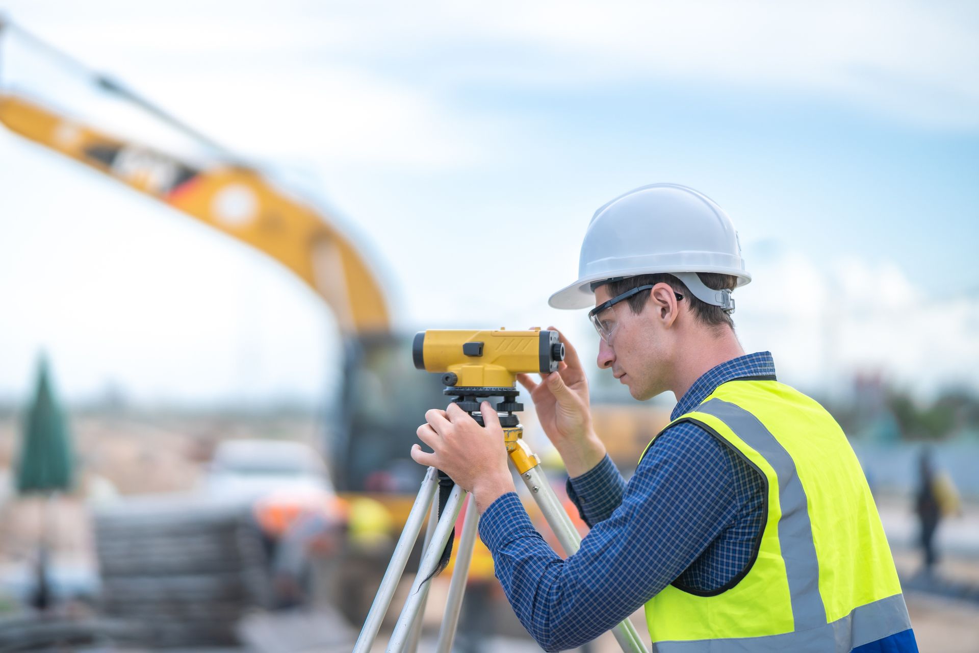 Male engineer and survey equipment working at construction site