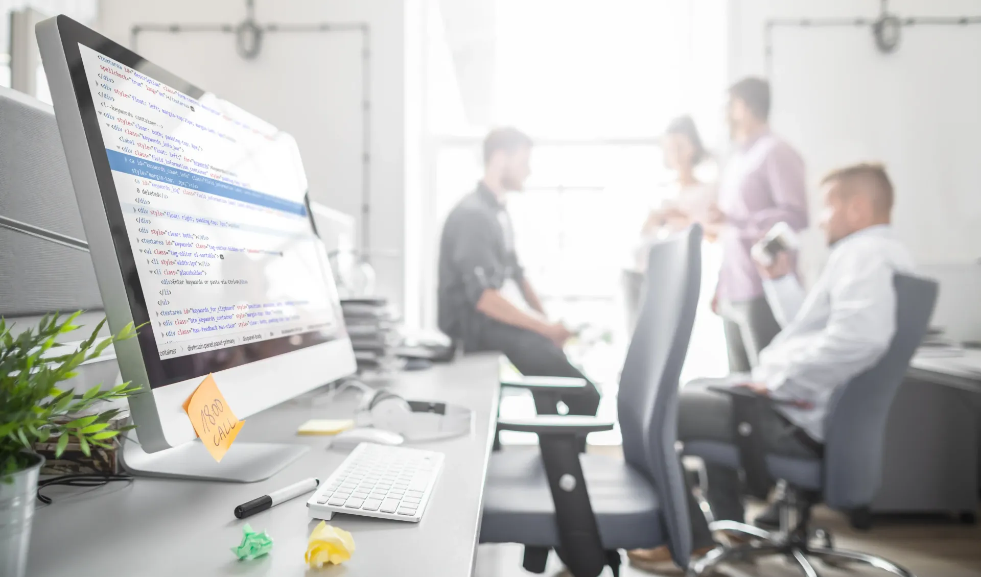 A group of people are sitting at a desk in front of a computer in an office.
