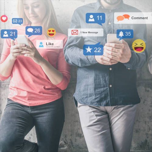 Zwei Personen lehnen an einer Wand und sind vertieft in ihre Smartphones, um die herum Benachrichtigungssymbole sozialer Medien schweben.