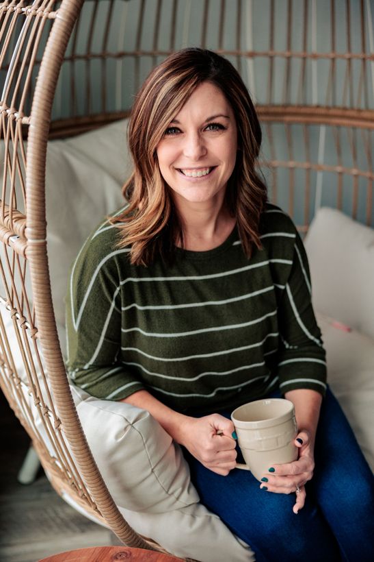 A woman is sitting at a desk with a laptop and a vase of flowers.