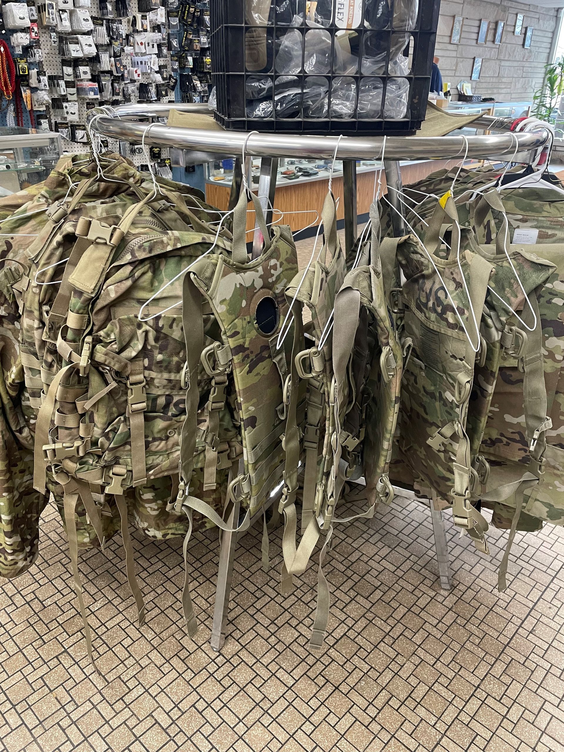 a bunch of military backpacks are hanging on a rack in a store