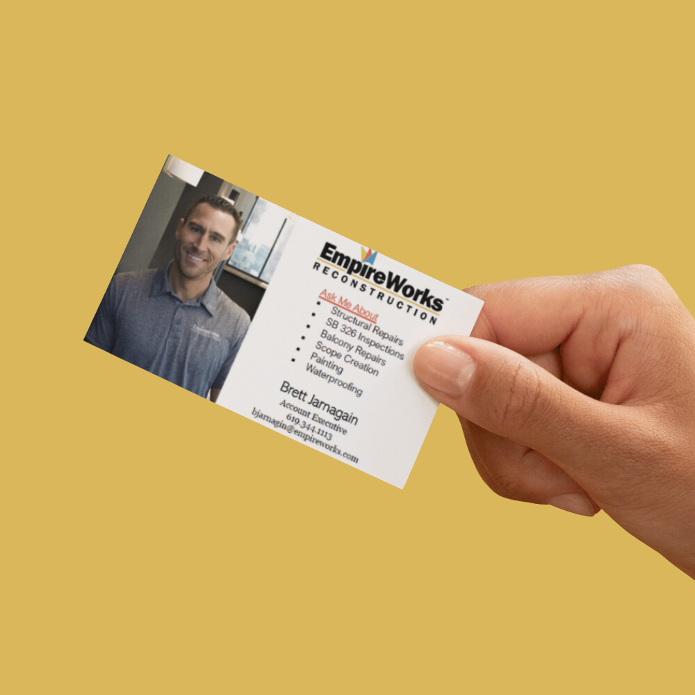 A hand is holding a business card for empire works reconstruction
