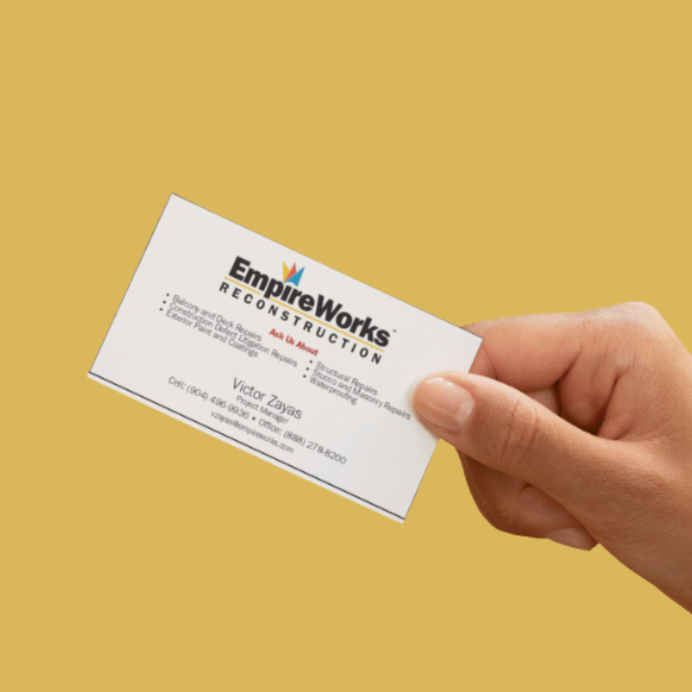 A hand is holding a business card for empire works reconstruction