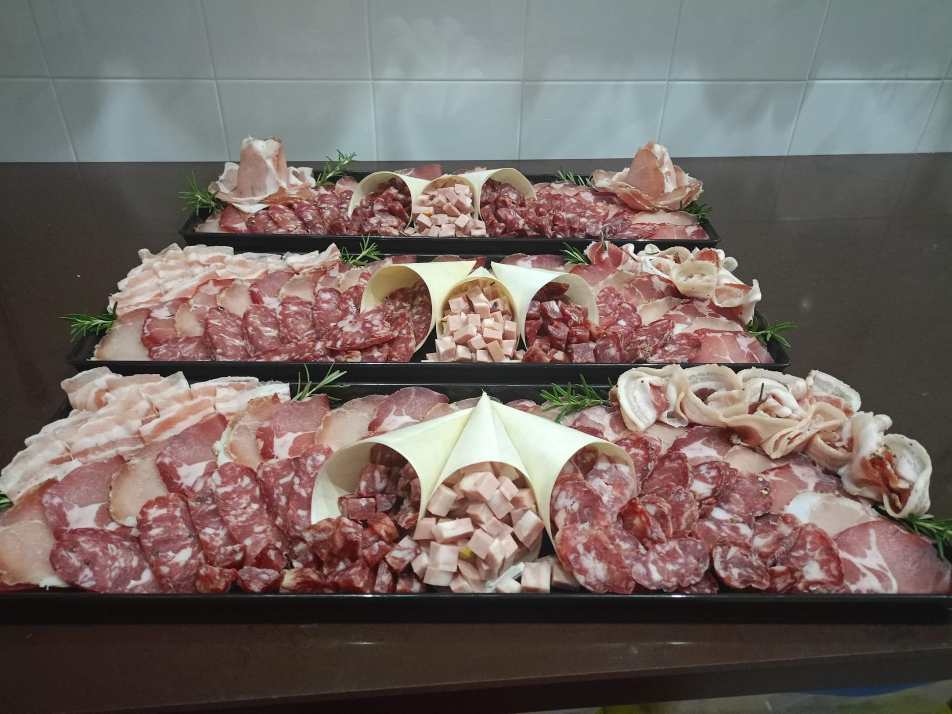 Tre vassoi con un assortimento di carne cruda e frutti di mare disposti su un tavolo
