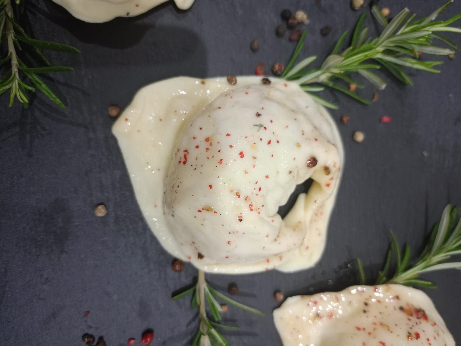 Conchiglie di pasta al forno con cremosa salsa bianca e rosmarino, servite su un piatto scuro.