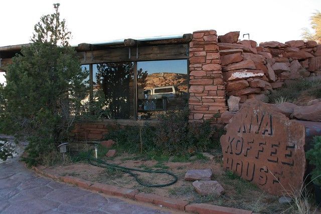 The red-stone Ava Koffee House building, set against a rocky desert landscape with a paved walkway.