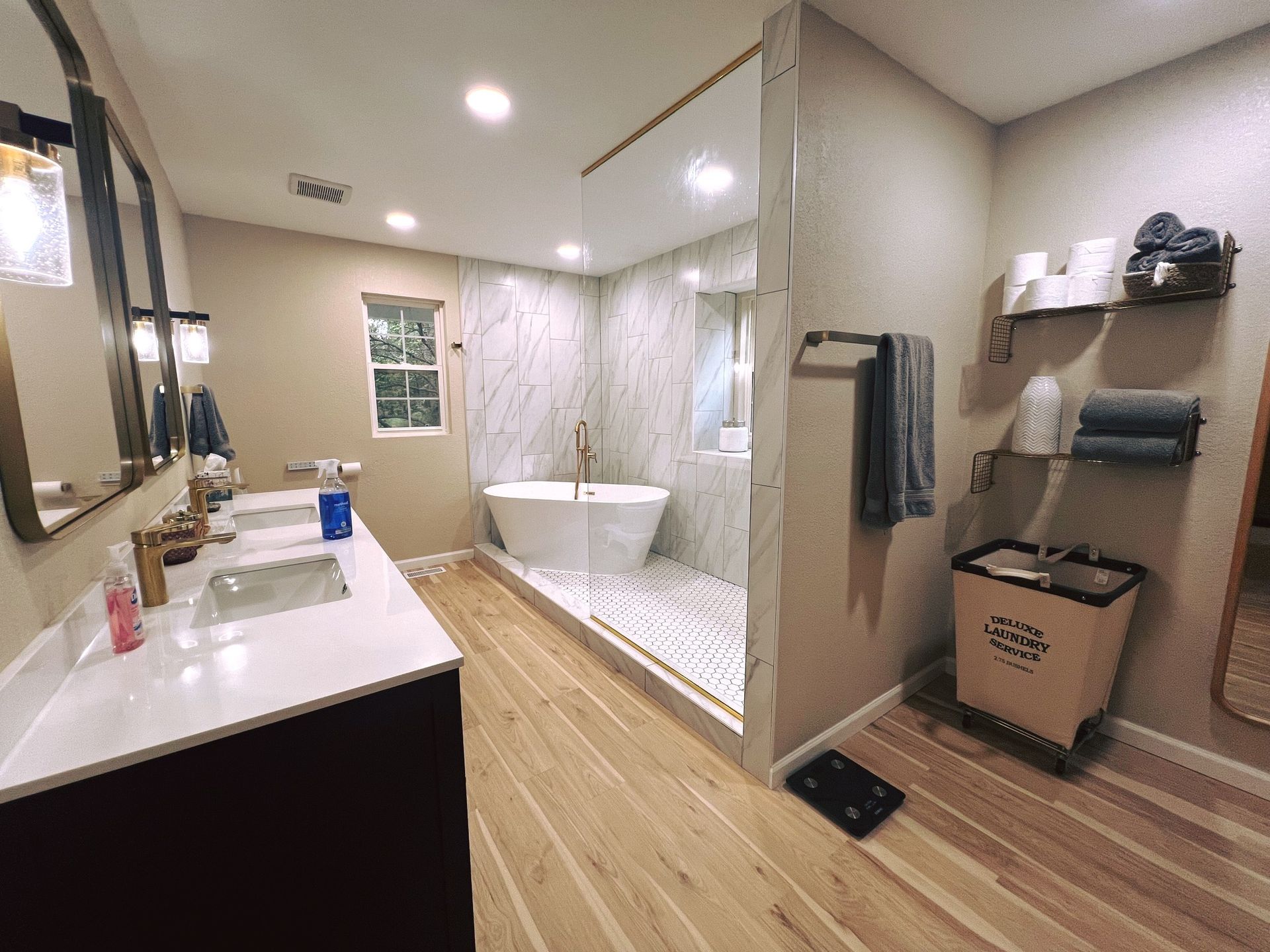 Spacious bathroom with a soaking tub, walk-in shower, and double vanity. Light wood floors, neutral walls.