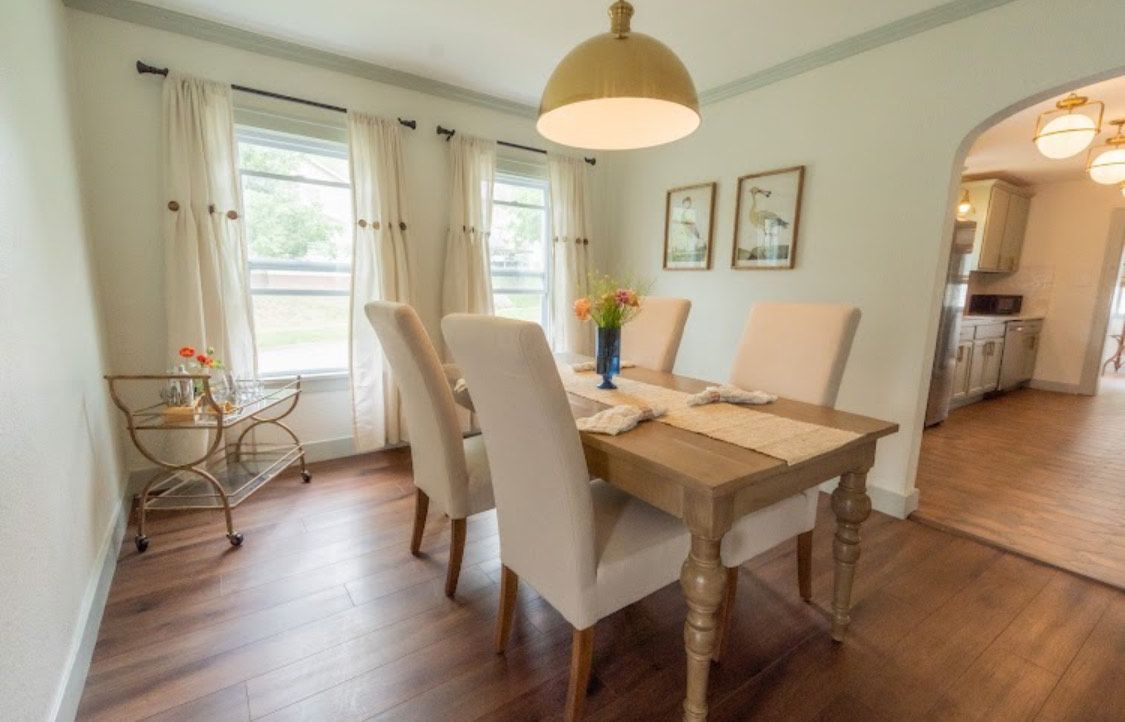 Dining room with a wooden table, cream chairs, and a golden light fixture.