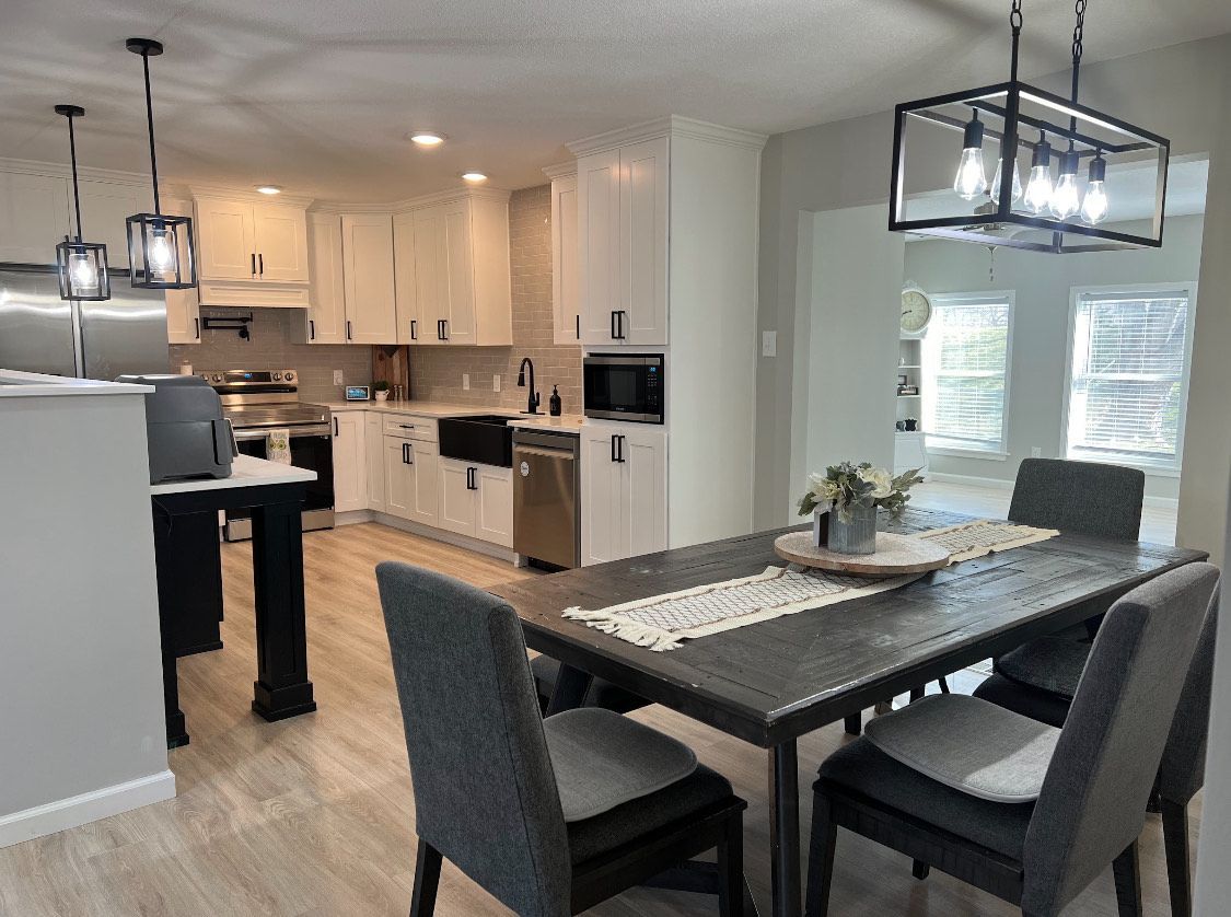 Kitchen with white cabinets, stainless steel appliances, dining table with chairs.