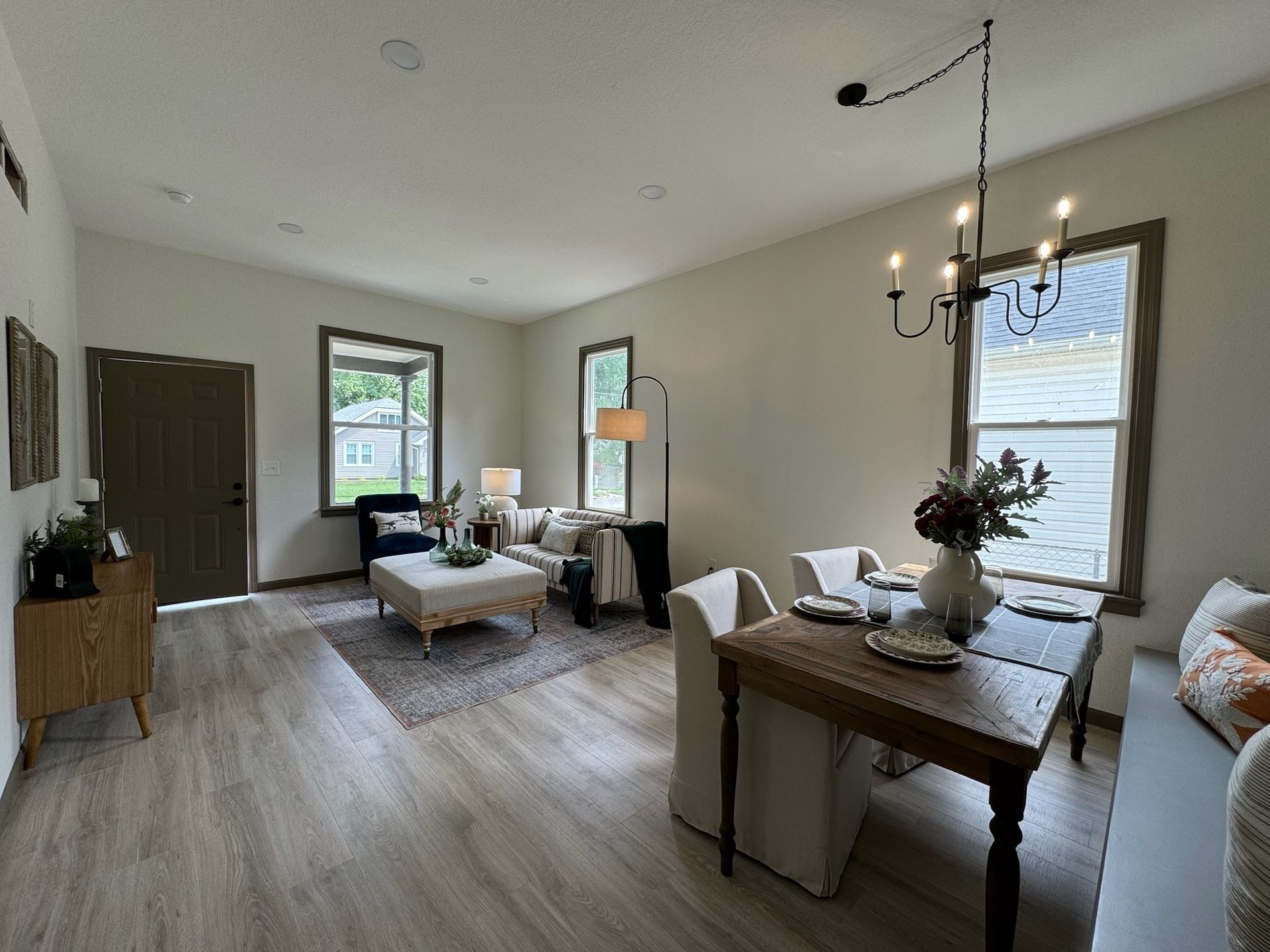 Living room and dining area with light wood floors, neutral walls, and dark wood accents.