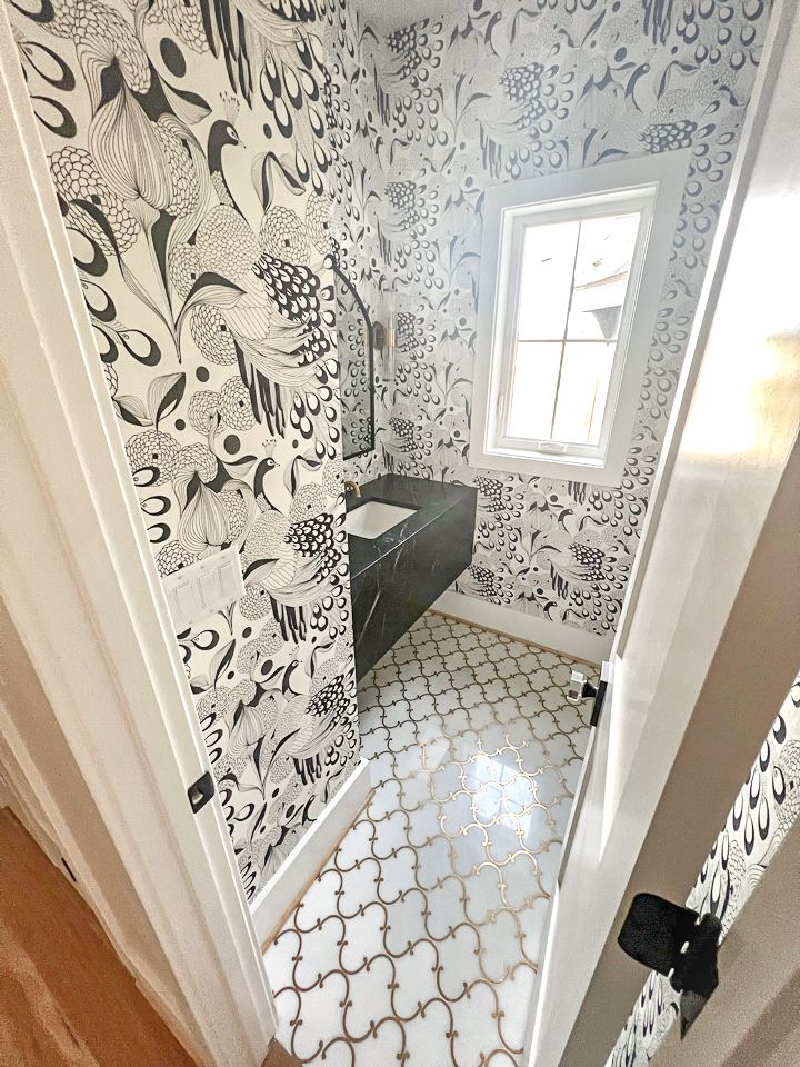 A bathroom with black and white wallpaper and a window.