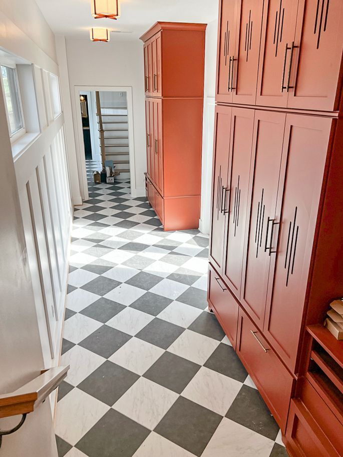 A hallway with a checkered floor and red cabinets