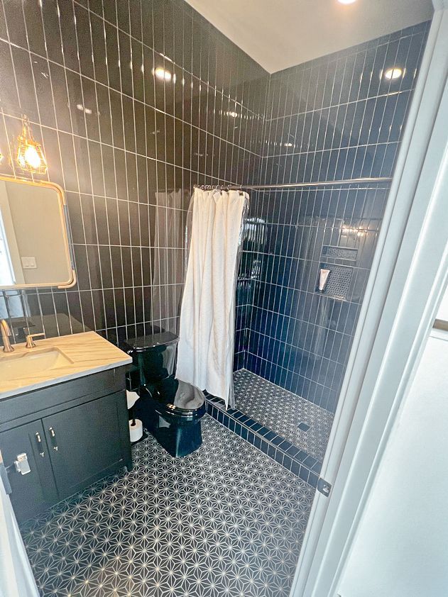 A bathroom with black tiles and a walk in shower.