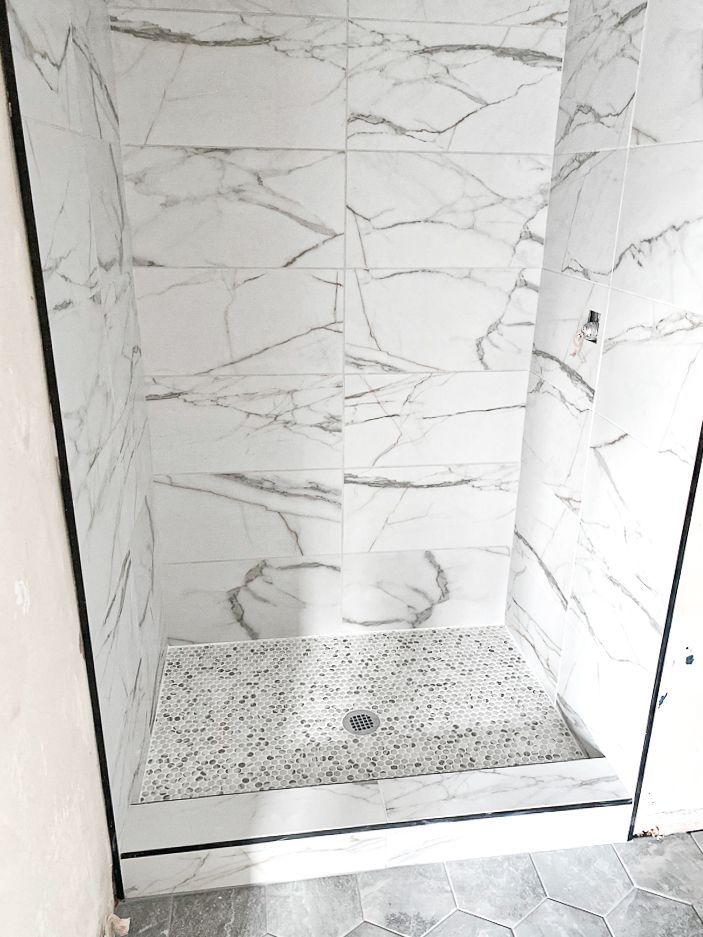 A bathroom with marble tiles and a walk in shower.