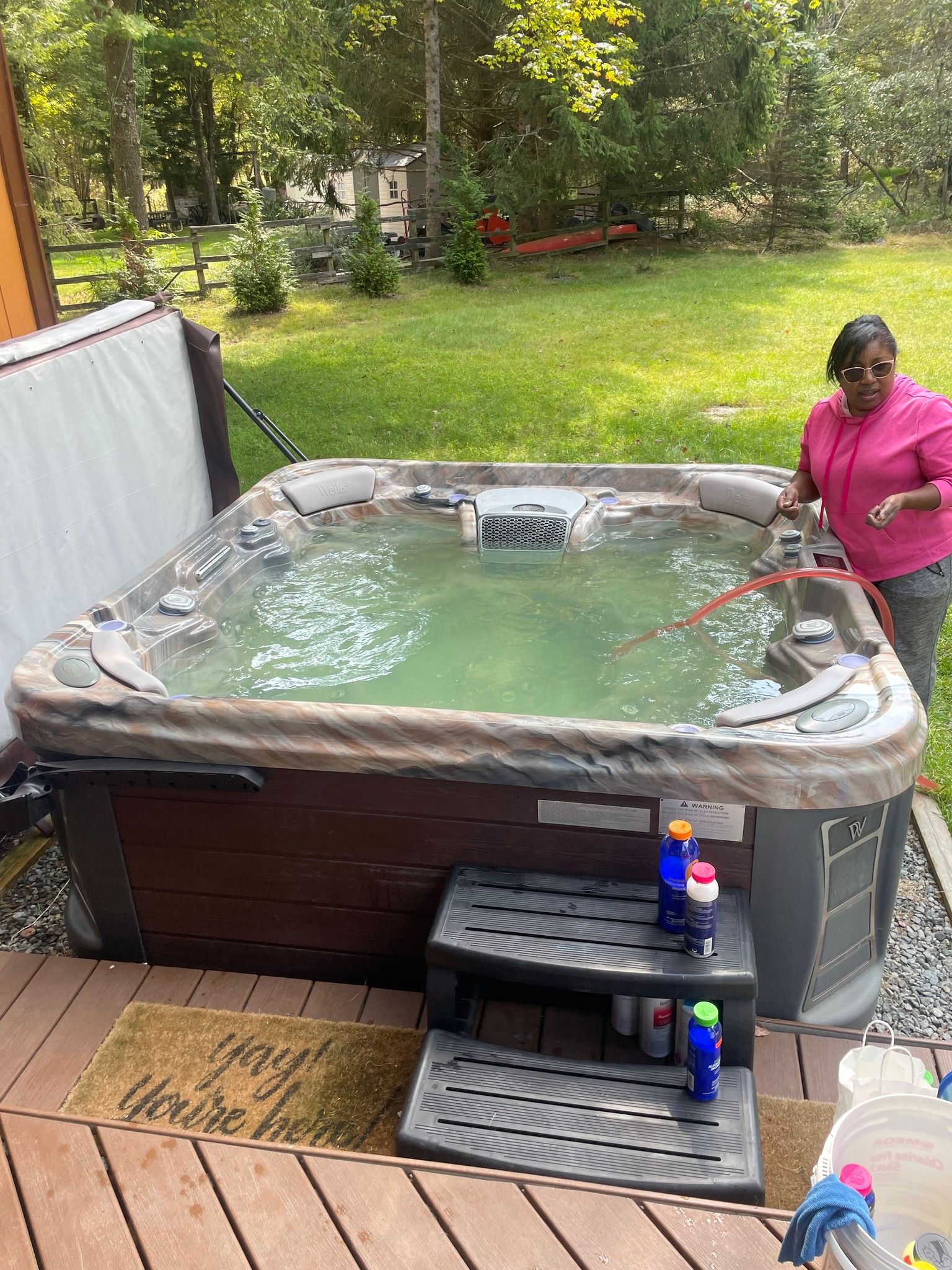 A woman is cleaning a hot tub on a deck.