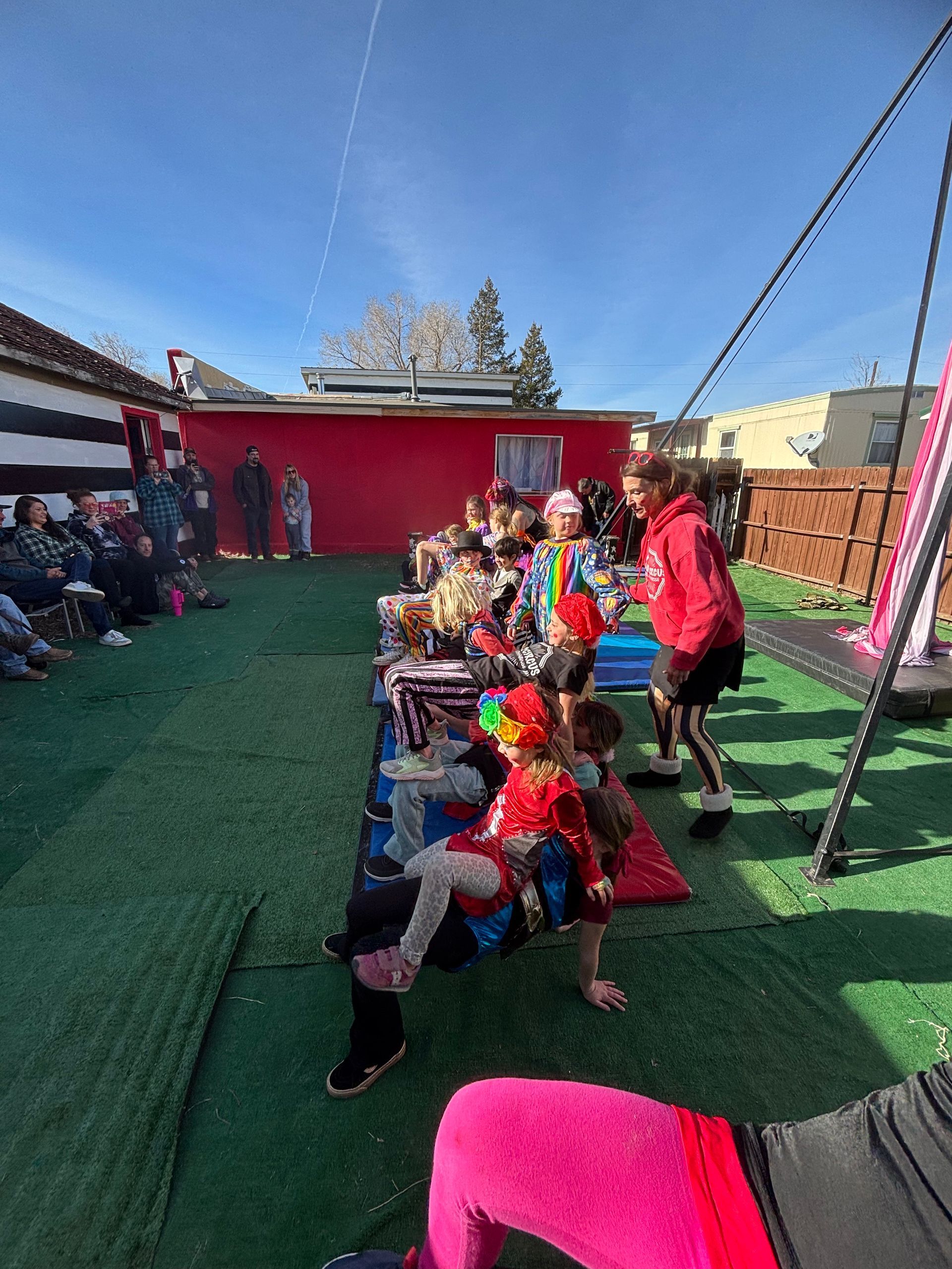Red building with small windows and a chimney, next to an unfinished building under a partly cloudy sky.