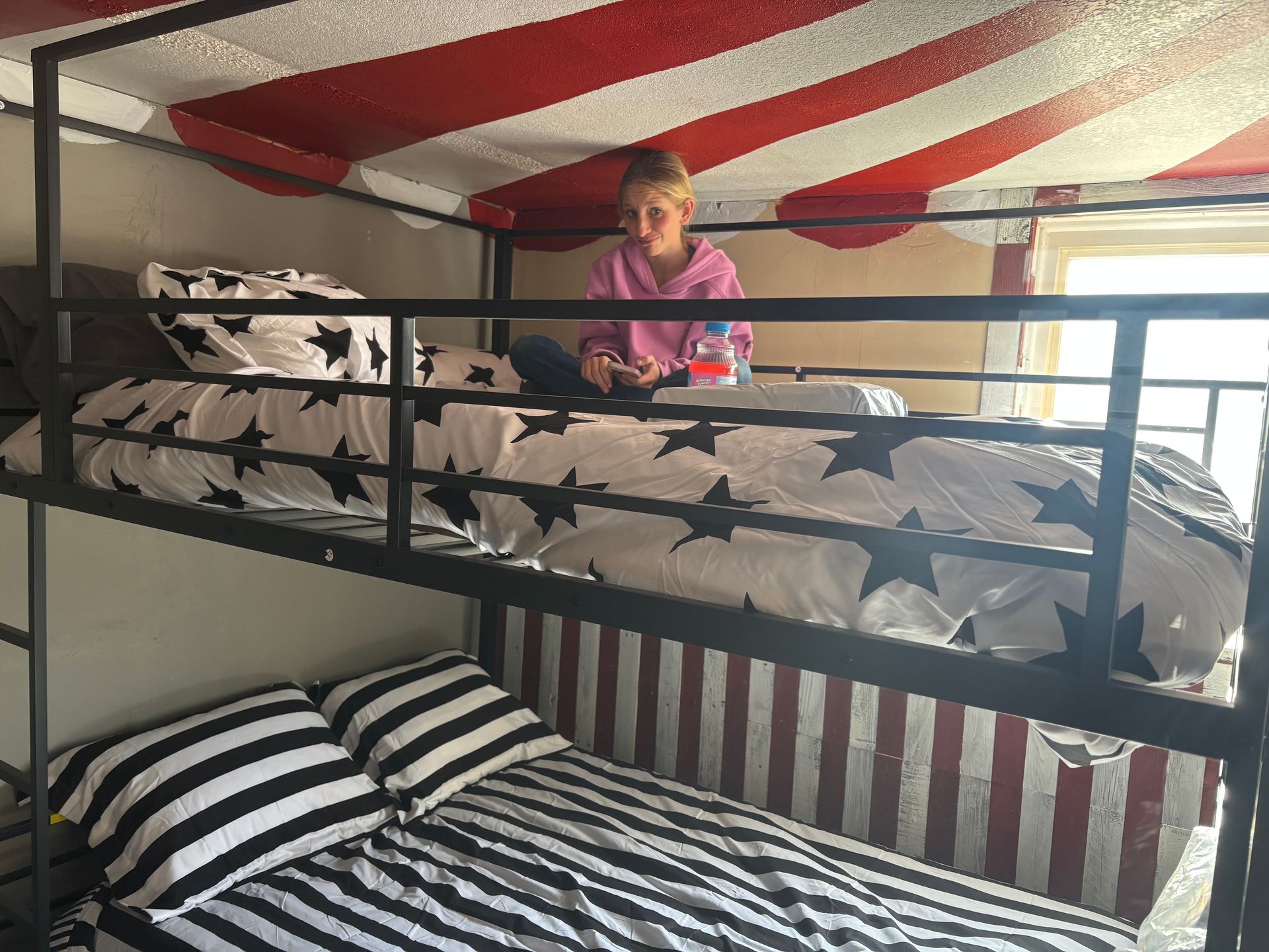 Room under renovation with two people, dog, blue wall, unfinished walls, and wood floor.