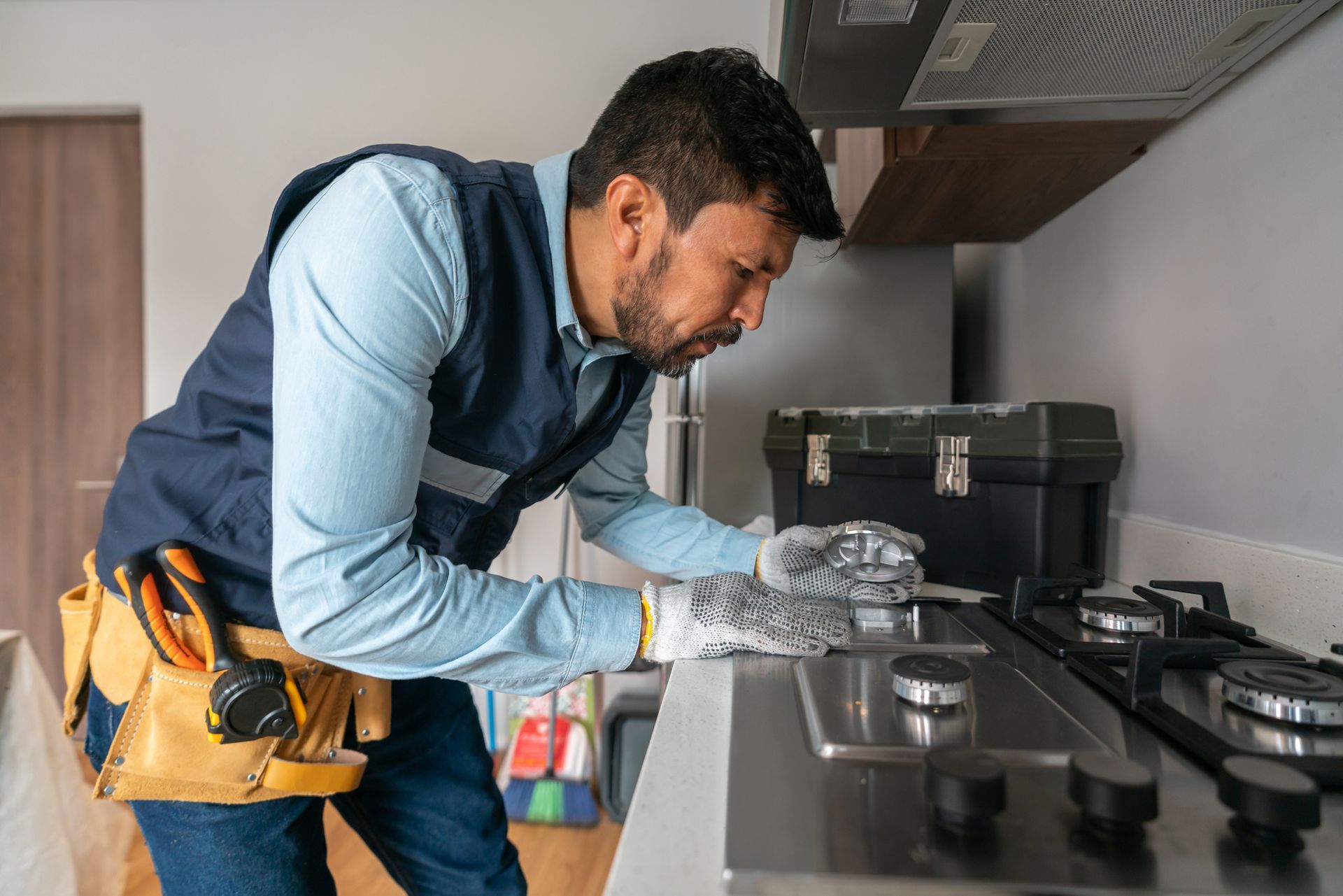 A man performing a gas inspection, carefully checking the stove for leaks with gas leak services.