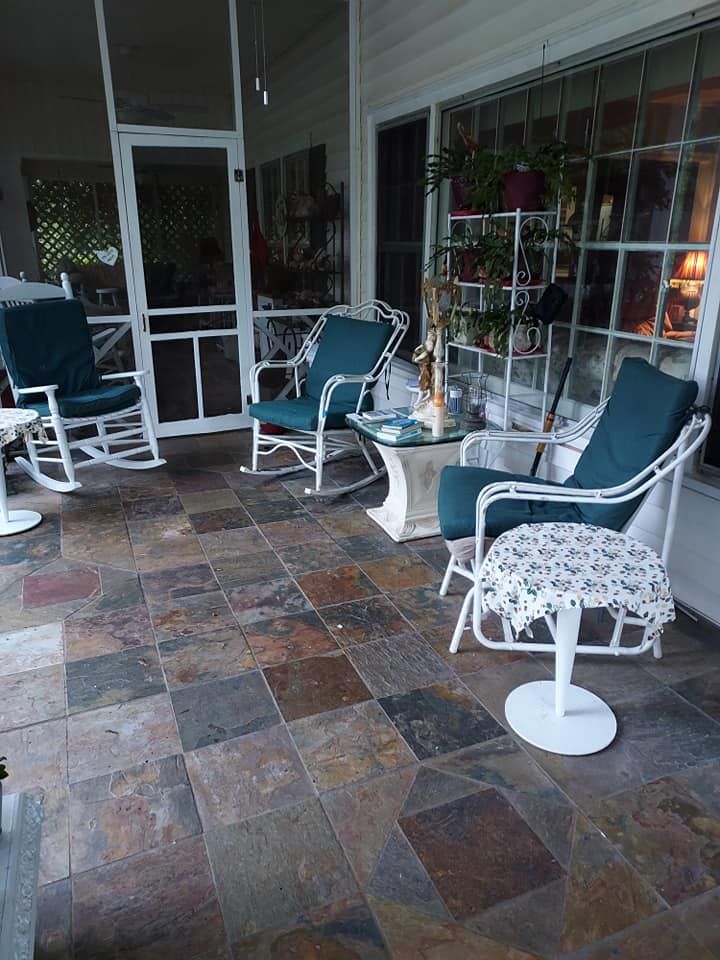 Patio with teal rocking chairs and stone tile floor.