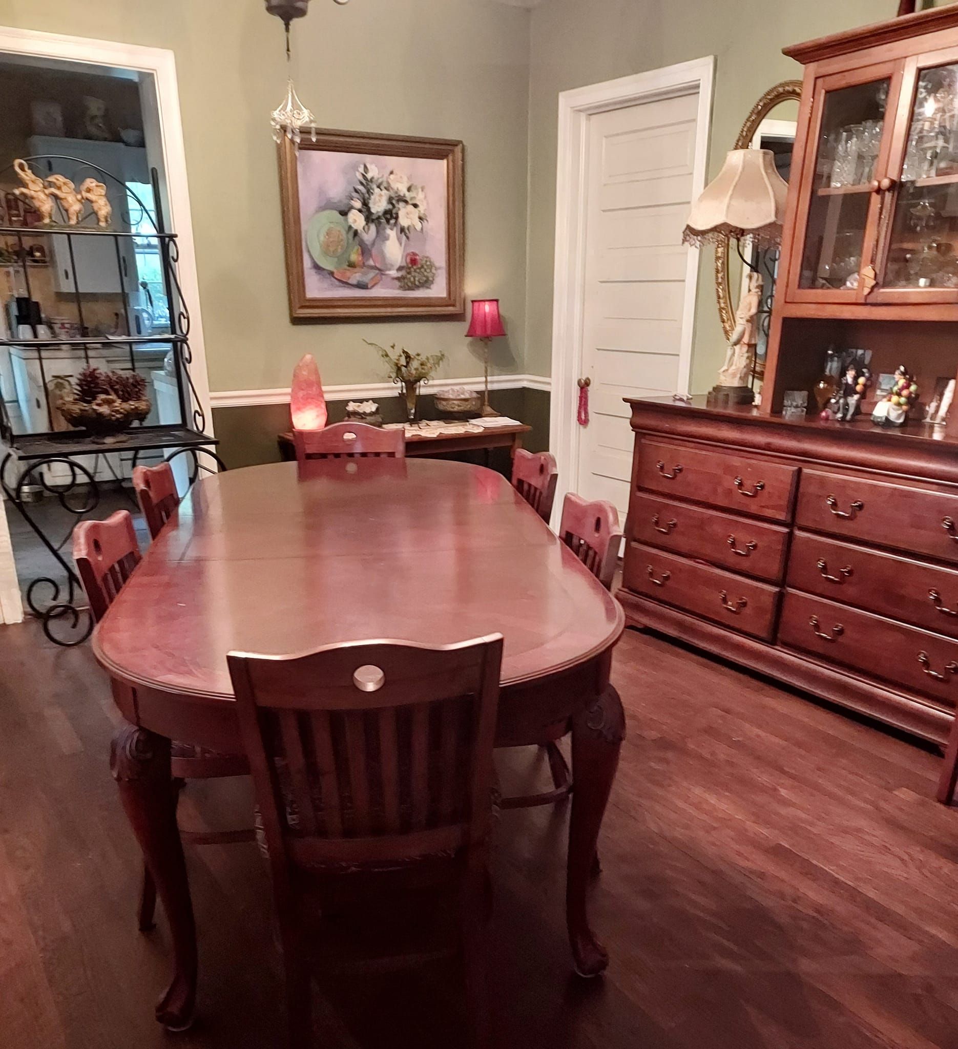 Formal dining room with wooden table, chairs, hutch, and art on the wall.