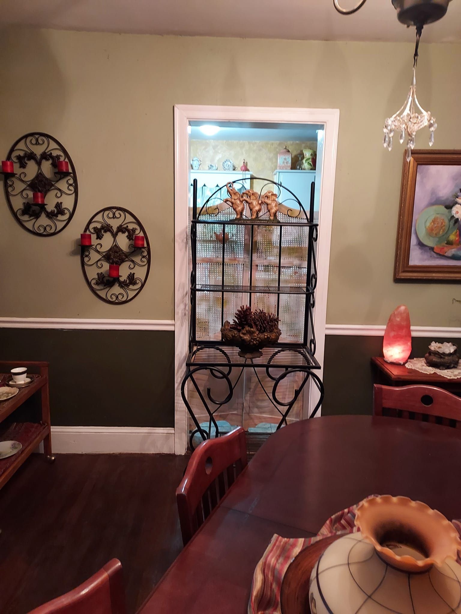 Dining room with dark wood furniture, sage walls, and a decorative cabinet.