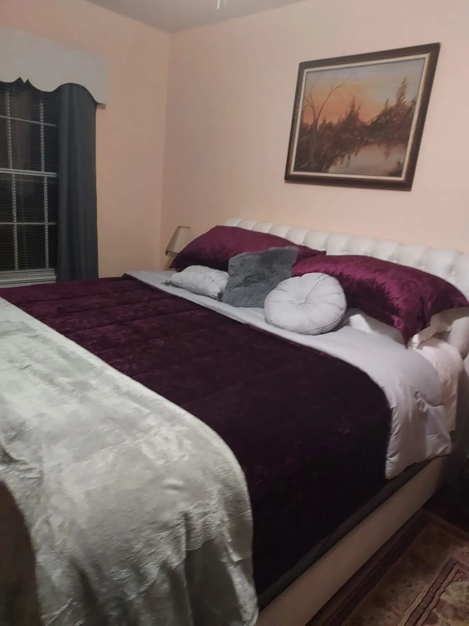 Two gray armchairs face each other, with a lamp and table between them. A painting hangs above.