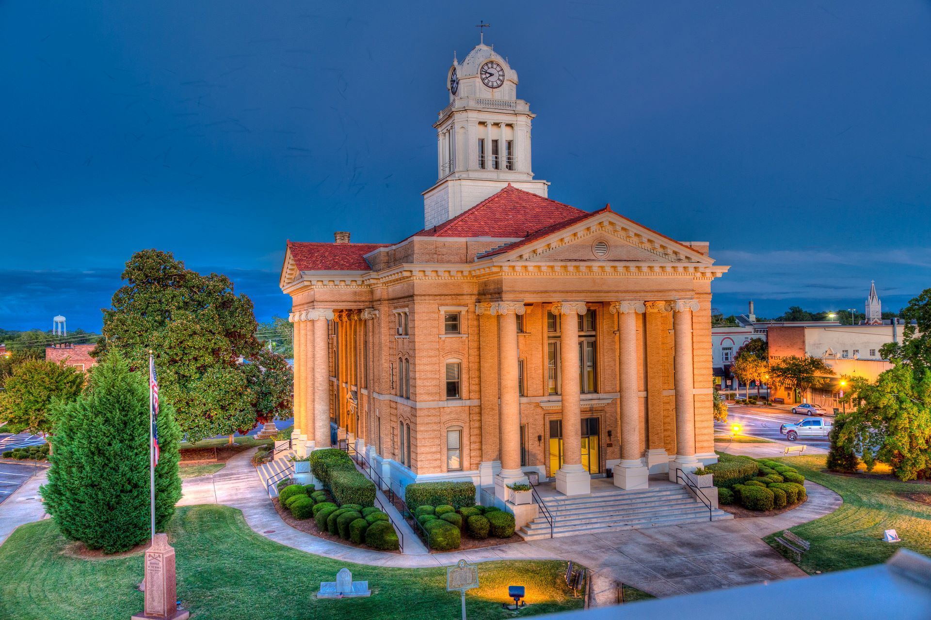 Brick courthouse with clock tower and pillars at dusk.