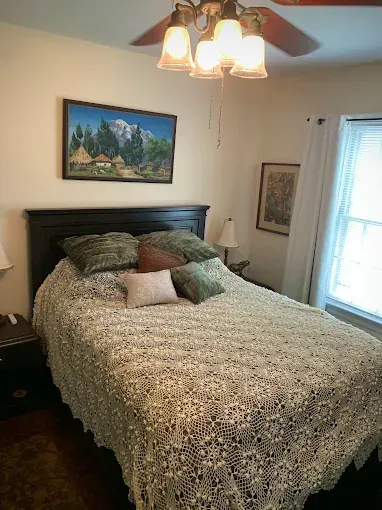 Two gray armchairs face each other, with a lamp and table between them. A painting hangs above.