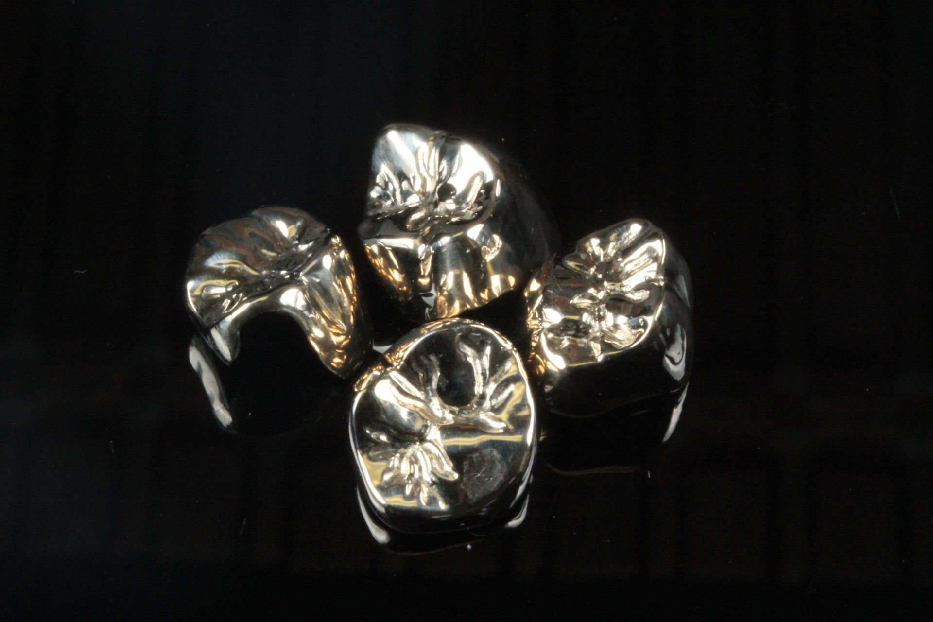 A group of dental crowns are sitting on top of each other on a black surface.