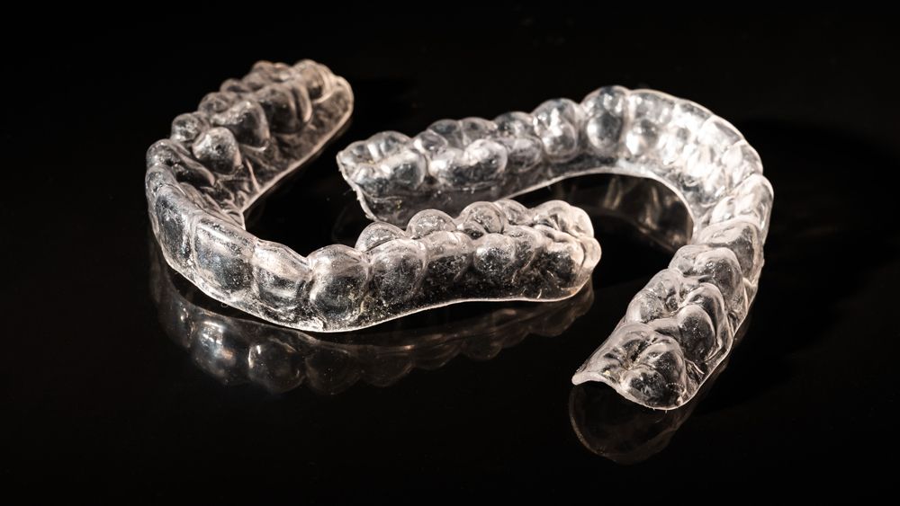 A clear mouth guard is laying on a black surface.