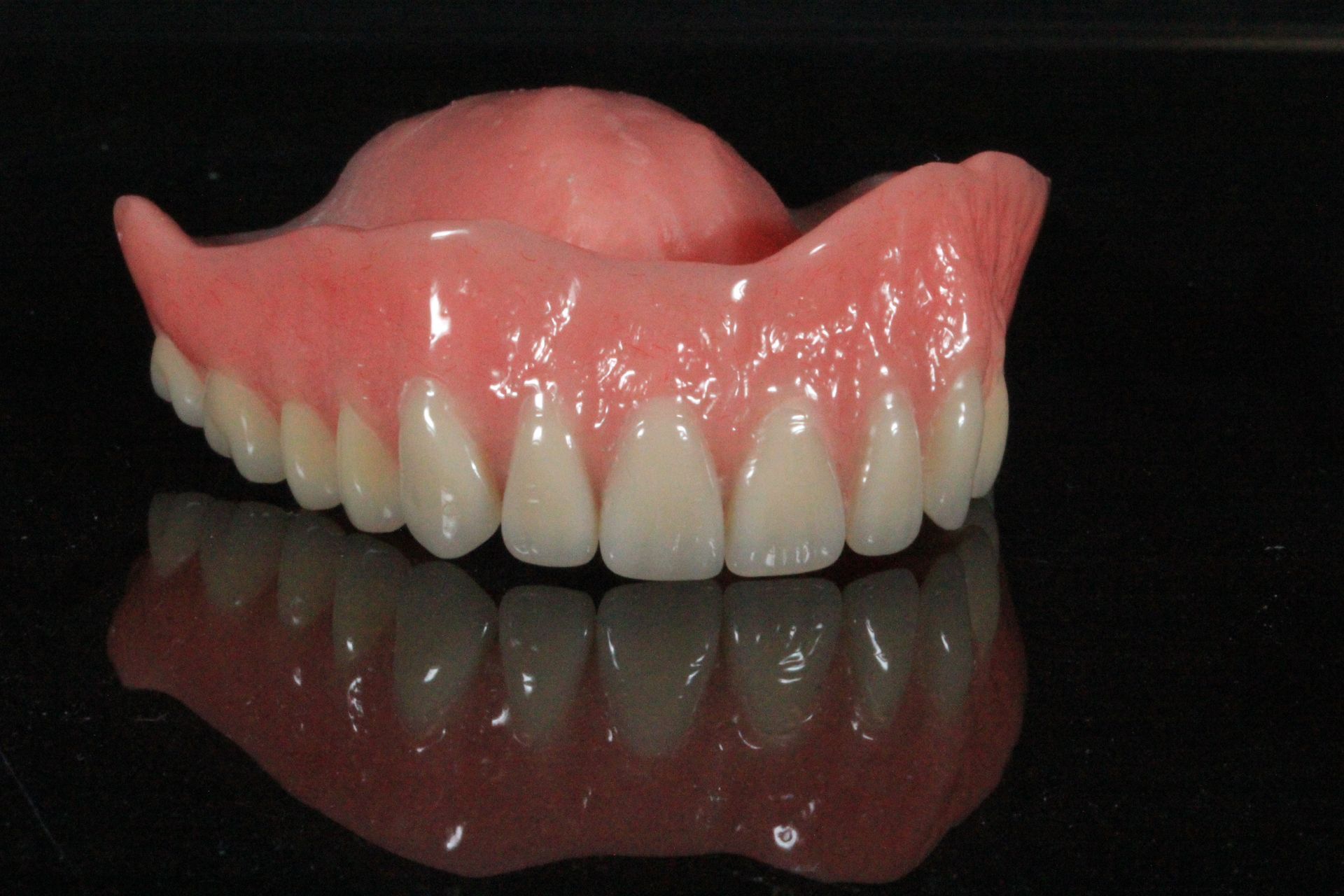 A close up of a denture on a black background