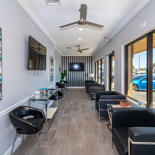 A long hallway with chairs tables and a flat screen tv