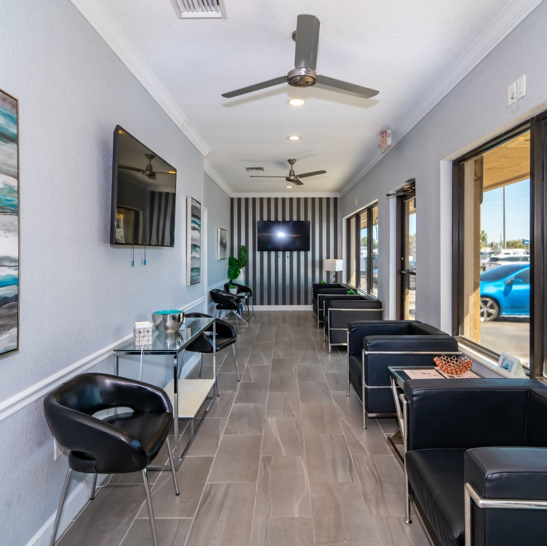 A long hallway with chairs and tables and a ceiling fan