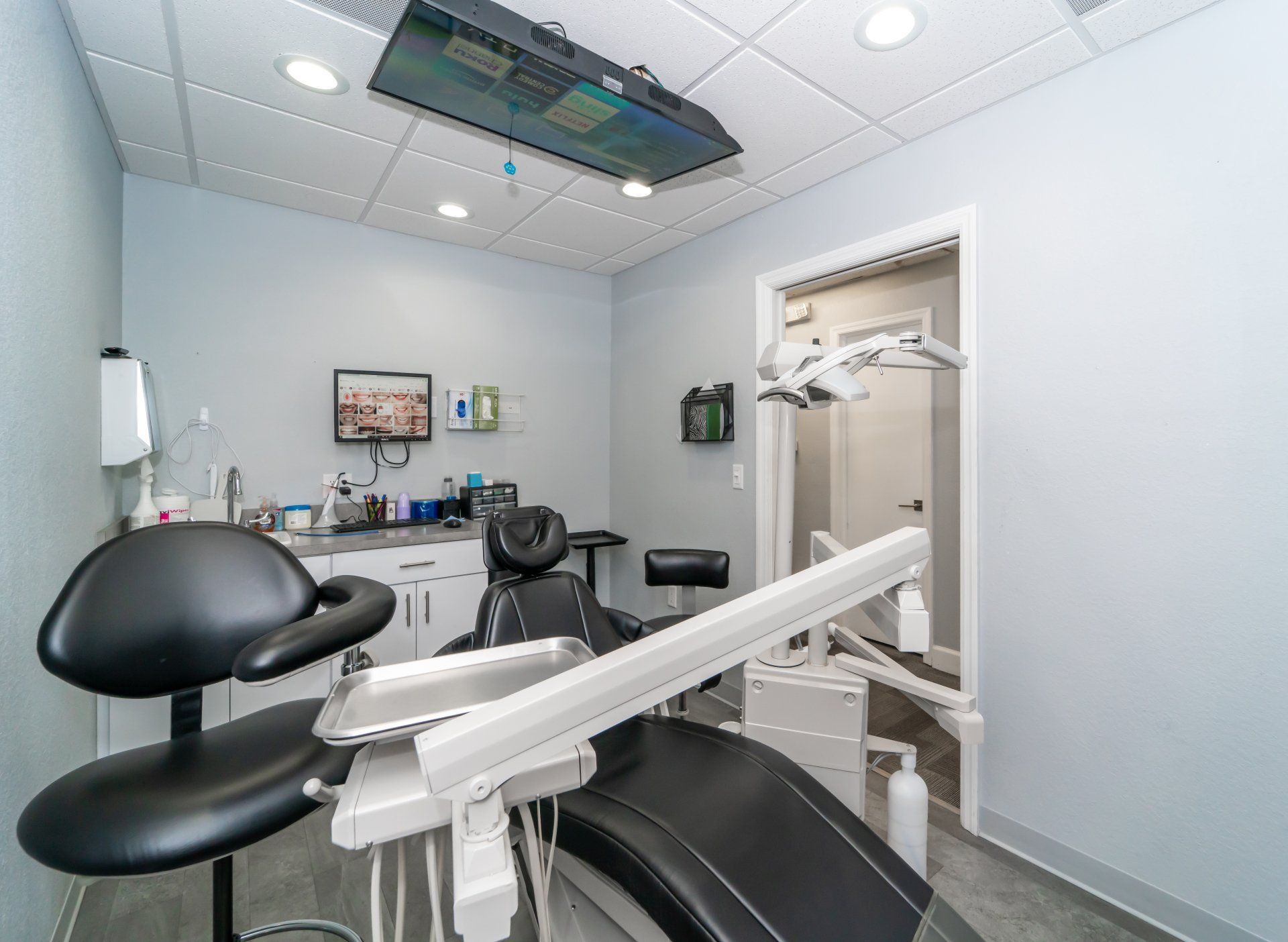 A dental office with a dental chair and a television on the ceiling.