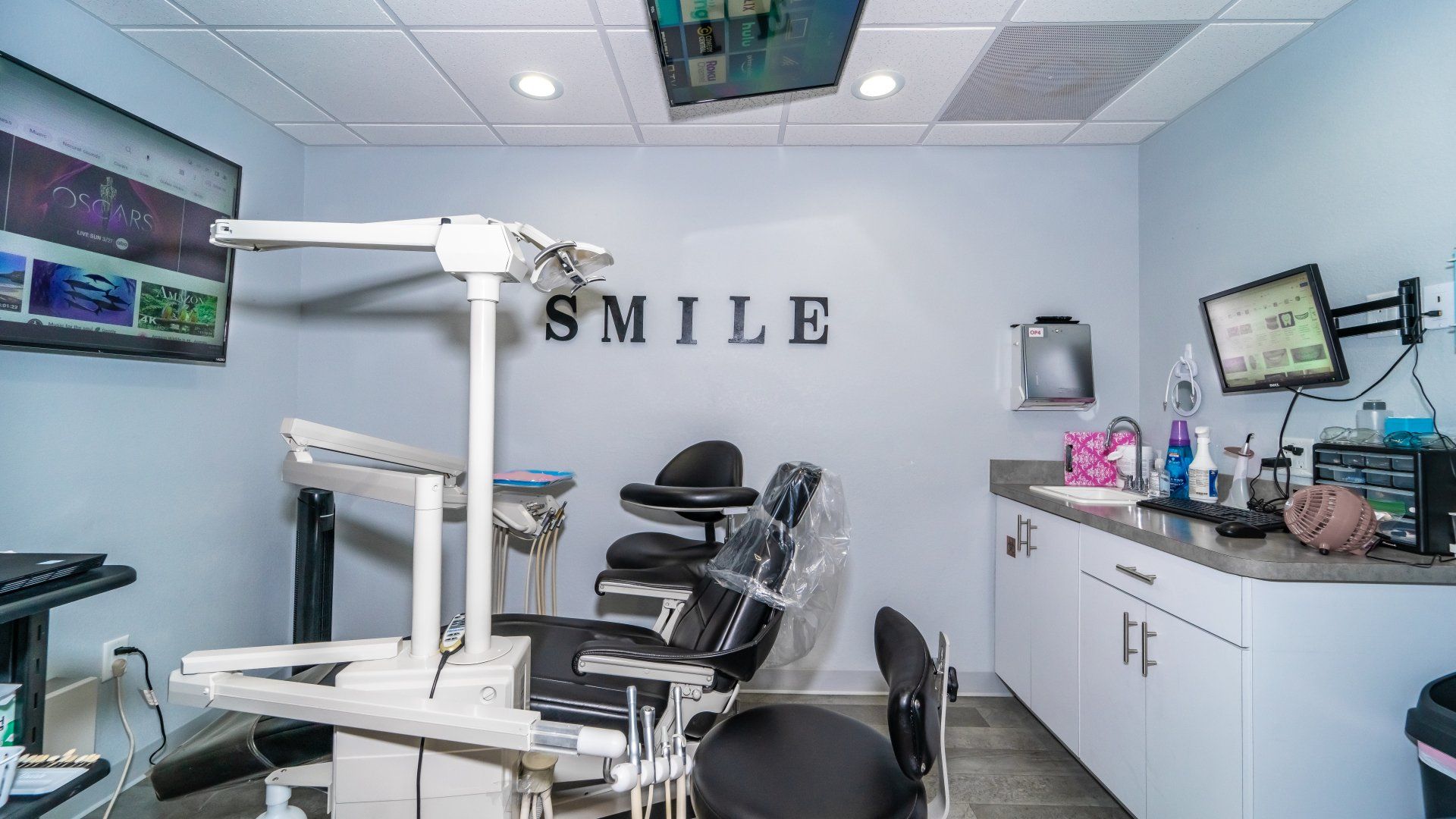 A dental office with a dental chair and a smile sign on the wall.