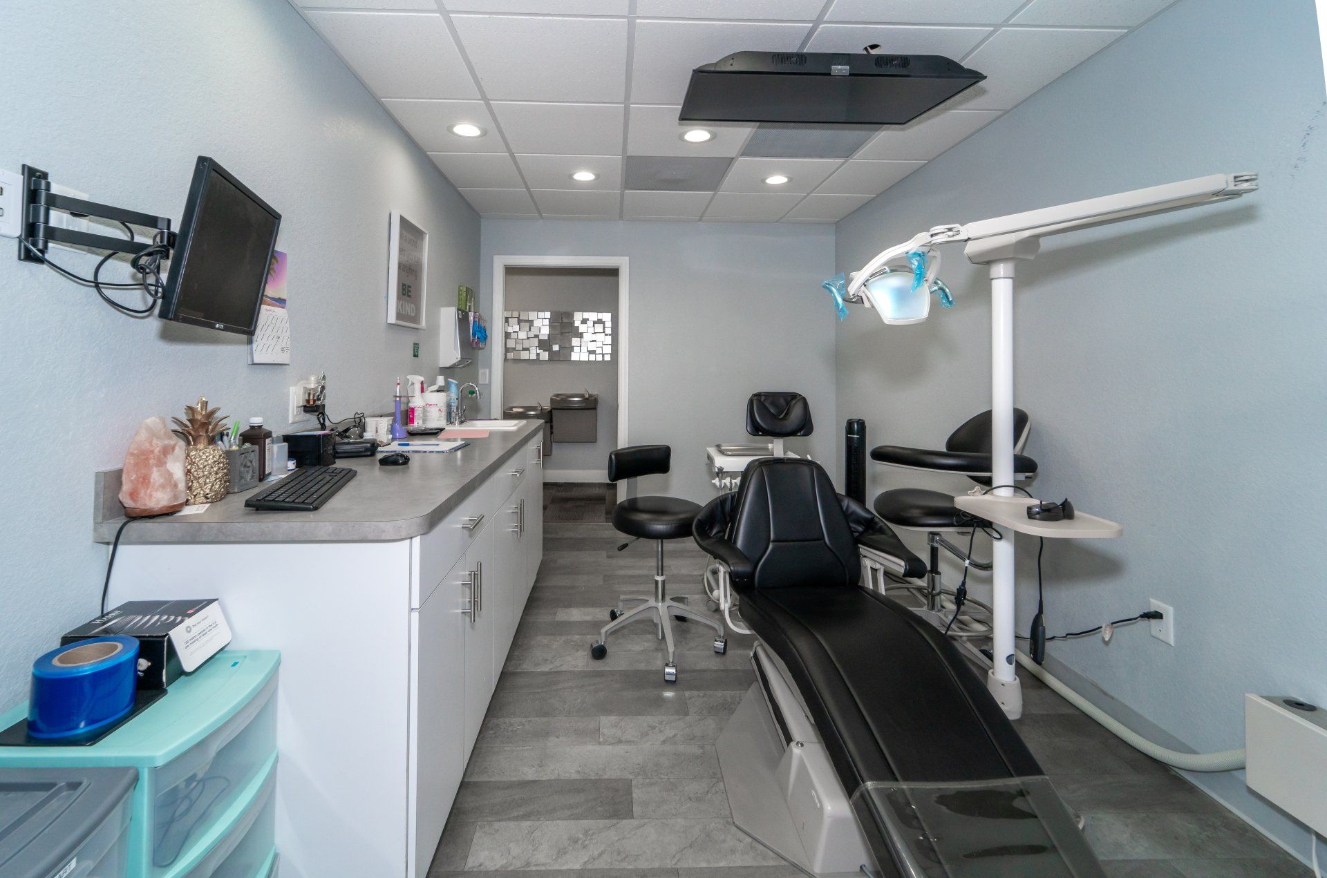 A dental office with a dental chair and a monitor on the wall.
