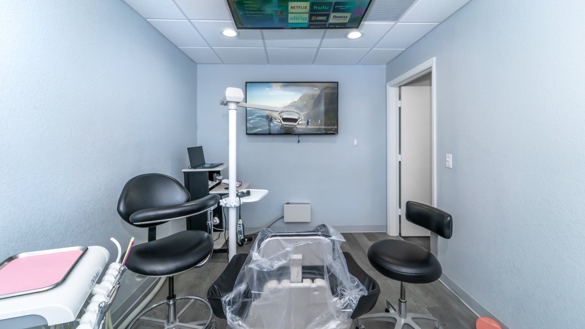 A dental office with a dental chair and a television on the wall.