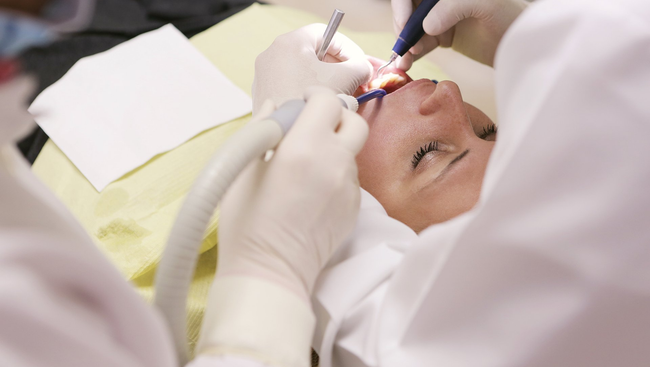 A woman is getting her teeth examined by a dentist