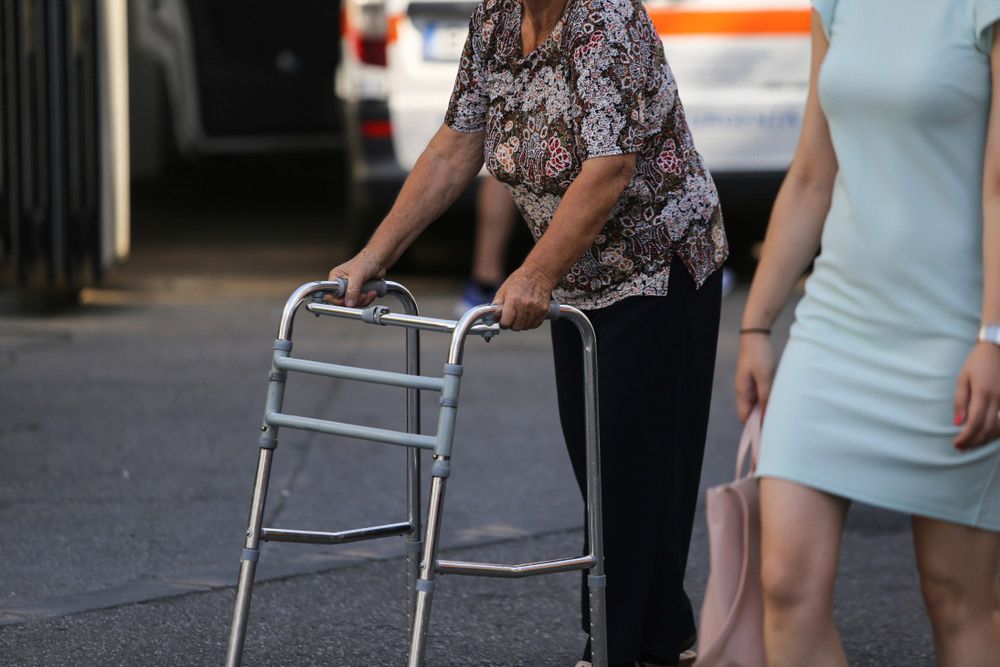 A Woman Is Using A Walker To Walk Down The Street — NQ Health In Bayview Heights, QLD