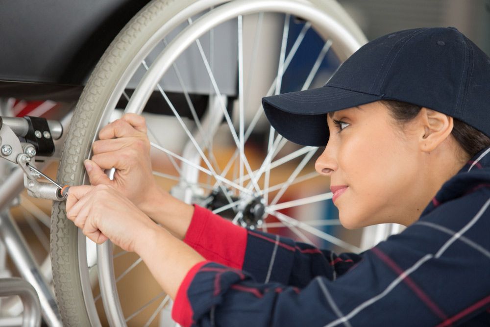A Woman Is Fixing A Wheelchair With A Wrench — NQ Health In Bayview Heights, QLD