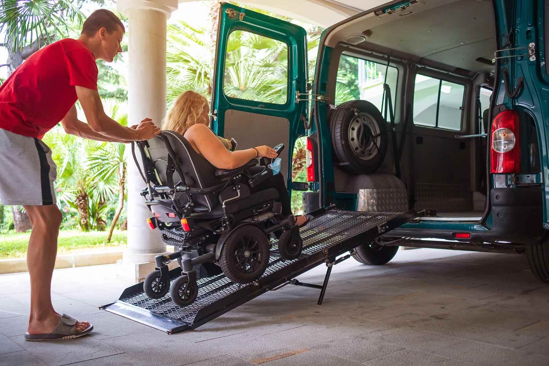 A Man Is Helping A Woman In A Wheelchair Into A Van — NQ Health In Bayview Heights, QLD