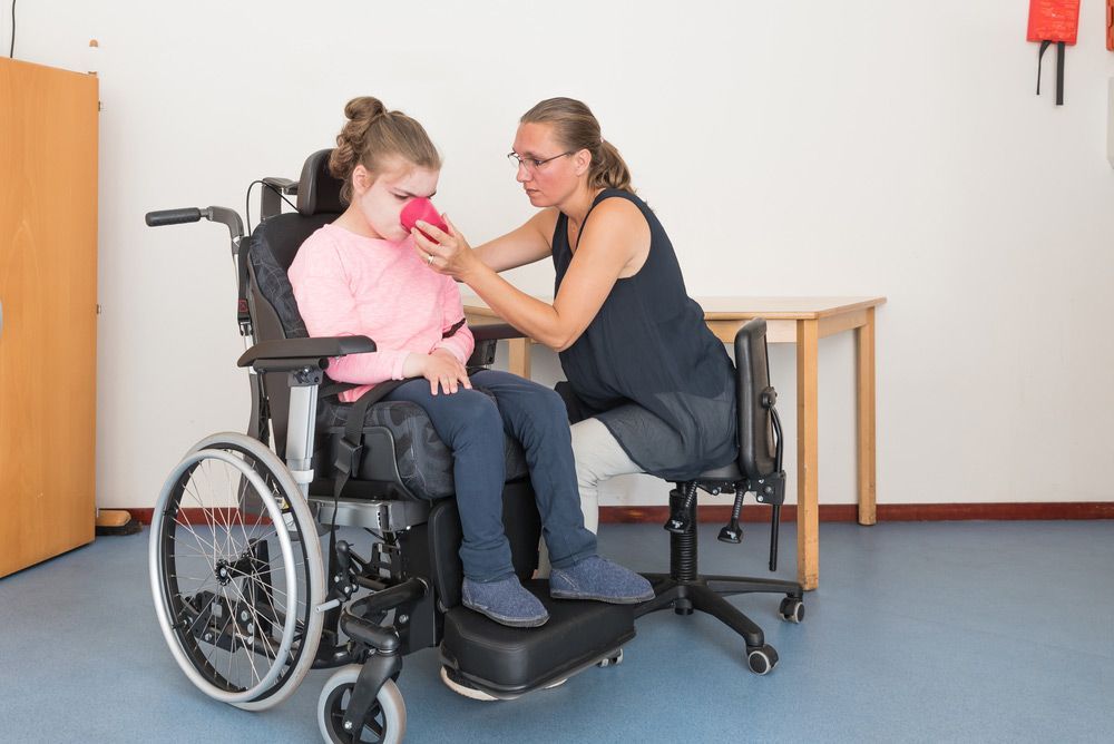 A Woman Is Helping A Young Girl In A Wheelchair — NQ Health In Bayview Heights, QLD