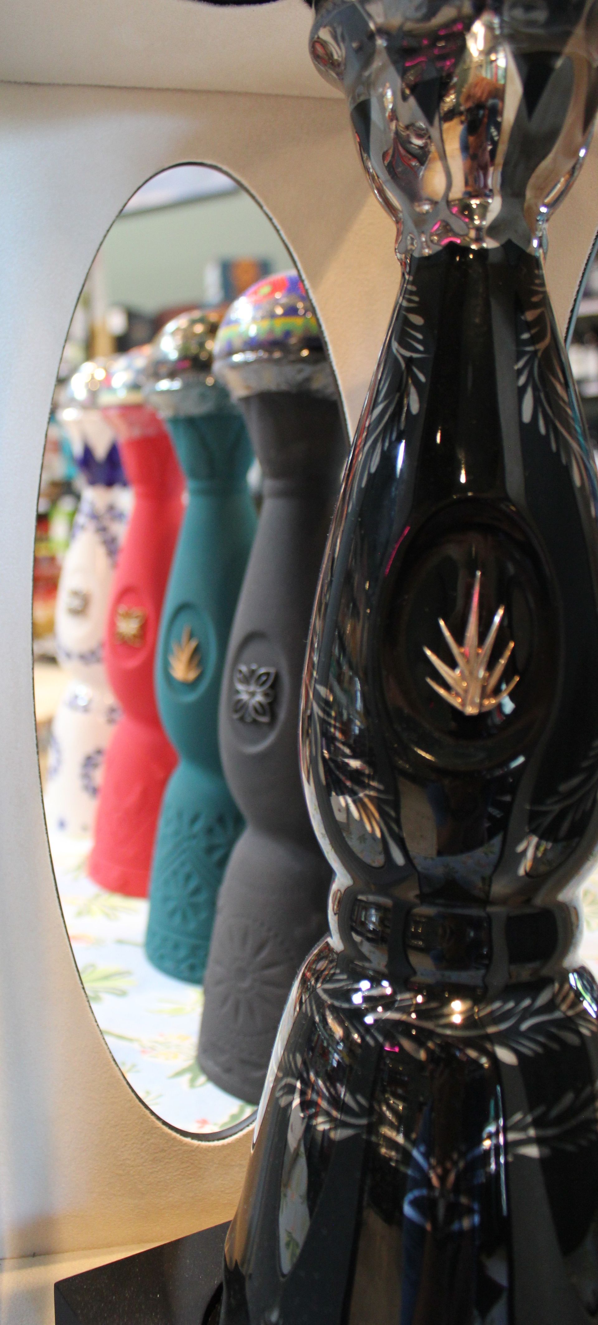 A row of bottles of tequila are lined up in front of a mirror.