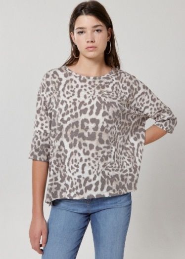 Una mujer que lleva un suéter con estampado de leopardo y jeans.