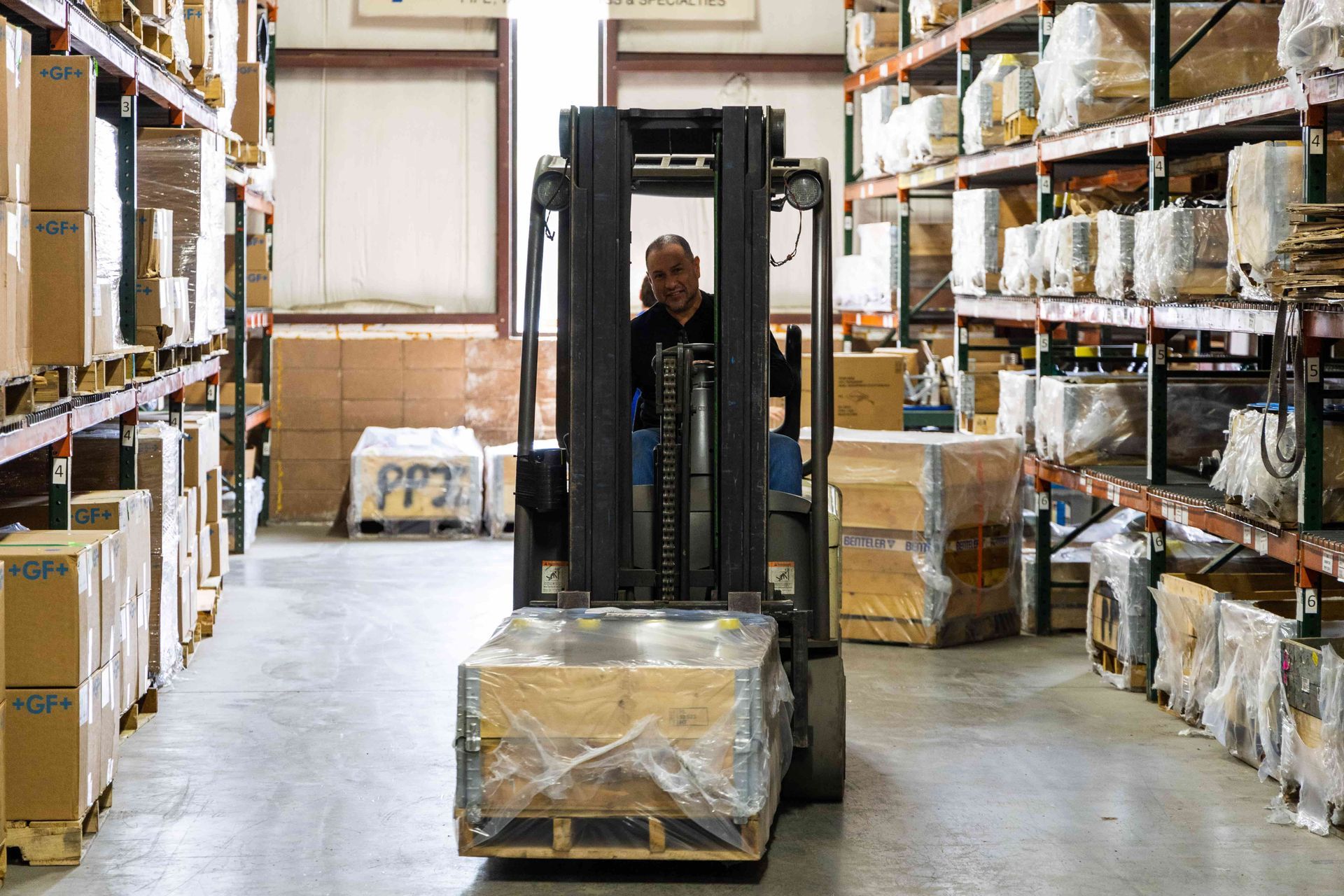 A man is driving a forklift in a warehouse.
