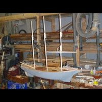 a model boat is sitting on top of a wooden table in a workshop .
